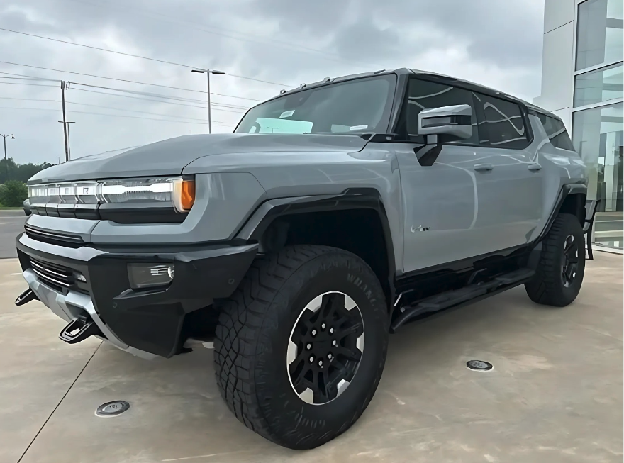 Front and side view of a GMC Hummer EV SUV in gray, equipped with CrabWalk mode, parked outside Crain Buick GMC in Conway